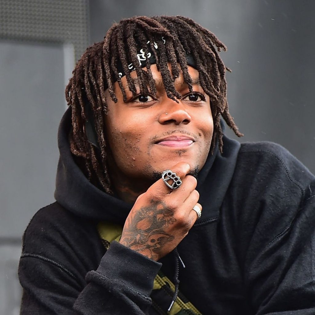 
            Image of Atlanta rapper JID smiling wearing a black bandana and hoodie with his tattooed hand on his chin.